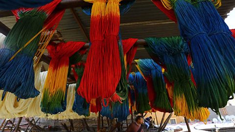 Multi-coloured cords of fabric knotted and draped over a wooden frame