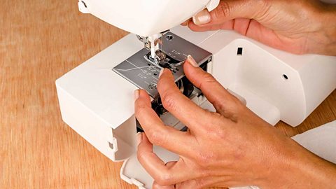 Hands making adjustments to a sewing machine