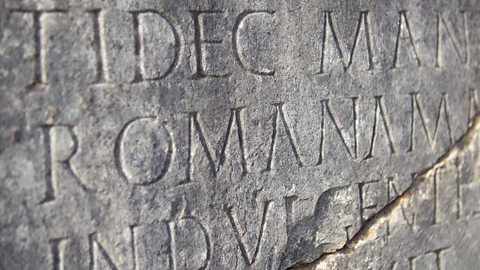 Latin writing carved on a cracked grey stone tablet