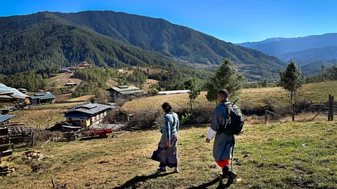 Nicole Melancon Host Dechen Zangmo and guide Singay Dradul hike near a Bumthang farmhouse (Credit: Nicole Melancon)