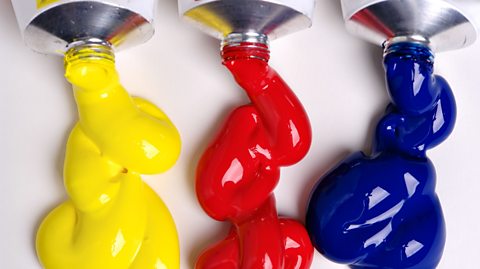 Three different tubes of paint. One is yellow, one red and the other is blue. 