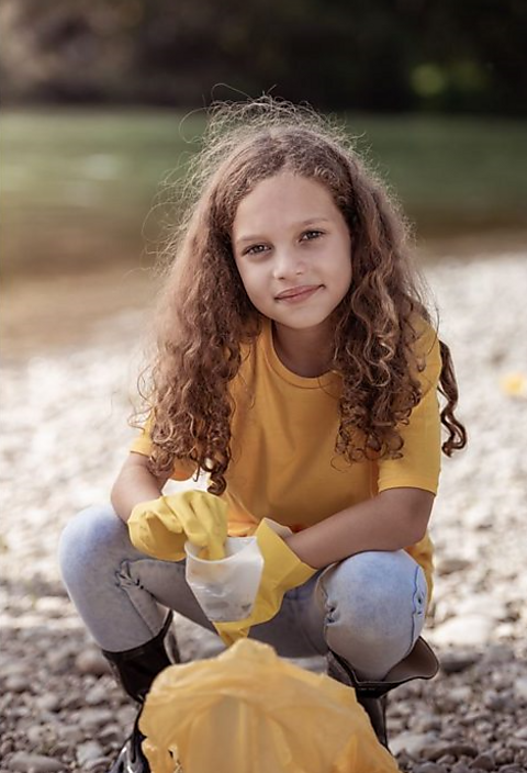 A girl picking litter from a beach.