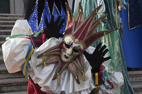 A person wearing a costume and decorated mask.