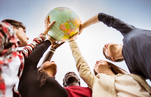 A group of people hold up a globe.