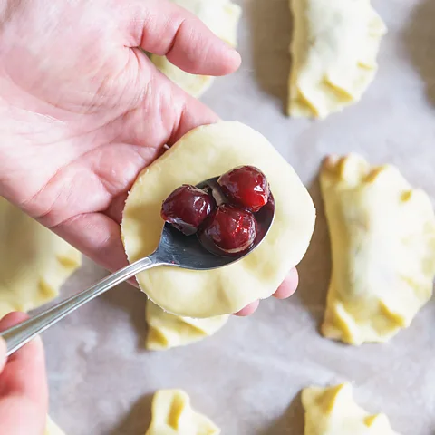 humonia/Getty Images Once cherries are placed in the middle of each varenyky, a pinch of sugar and a sprinkling of flour is added (Credit: humonia/Getty Images)