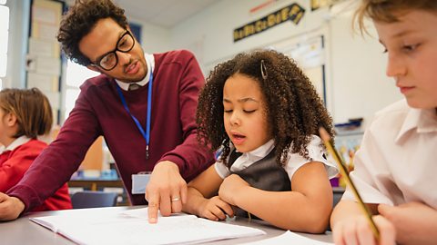 A teacher pointing at a primary school girl's exercise book.