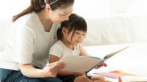 A mum and her daughter looking at a picture book.