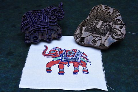 Two woodcut stamps of elephants with a colourful print on fabric