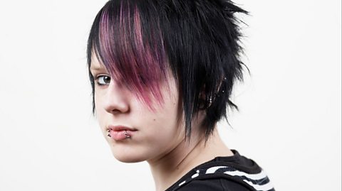 An emo kid with sweeping pink and black fringe and lip piercings.