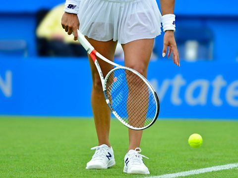 A tennis player bouncing a tennis ball.