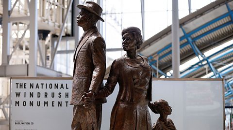 The National Windrush Monument created by Jamaican artist Basil Watson. It show three figures holding hands - a man in a hat, a woman and a child.