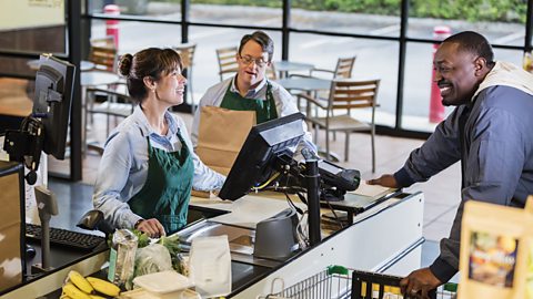 Customer and employees at supermarket checkout