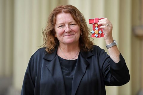 Rachel Whiteread smiling at the camera, holding up her medal