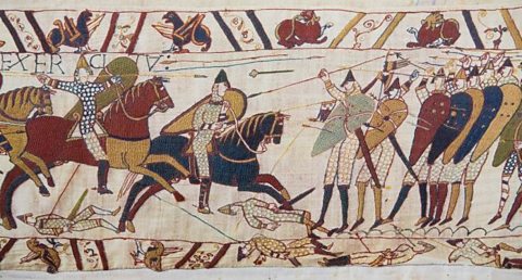 A small section of The Bayeux Tapestry. It shows people riding horses and throwing spears.