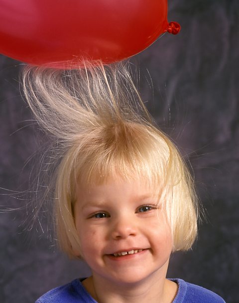 A girl's hair being attracted to a balloon.