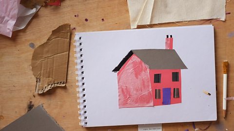 A collage of a house on a piece of paper and some materials and pencil around it