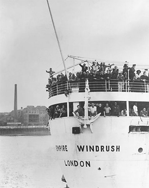 The back of the Empire Windrush is shown as it sails up the Thames. From two separate decks, smiling people - mainly young black men - can be seen.