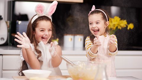 Two children - one with bunny ears on, doing Easter baking 