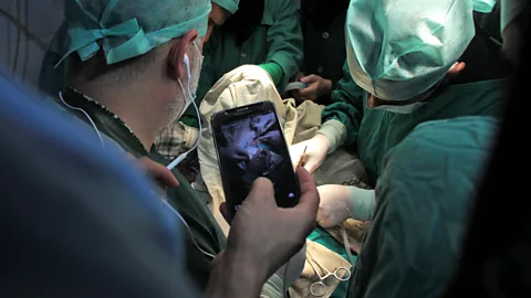 Getty Images A surgeon conducts a consultation using a mobile phone (Credit: Getty Images)