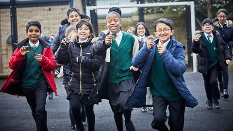 A group of schoolchildren running in playground with micro:bits