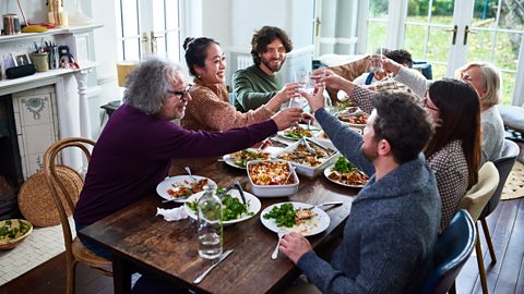 Large family gathering making a toast around the dinner table at lunch