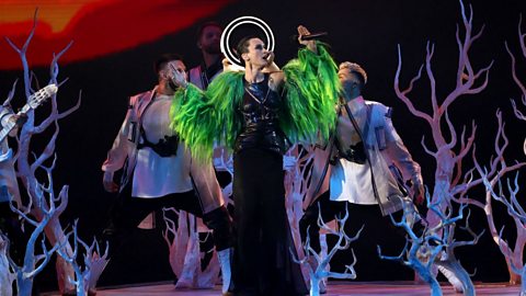 Go_A lead singer Kateryna Pavlenko on the Eurovision 2021 stage, dressed in a black dress and a green feather bolero.