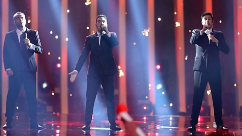 Ethno-Jazz Band Iriao of Georgia perform during the second semi-final of the 2018 Eurovision Song Contest. They are three white men wearing dark suits.