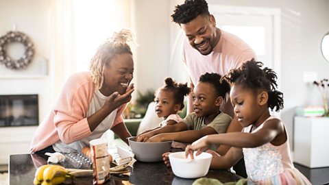 Mother, father and three young children enjoy time together baking 