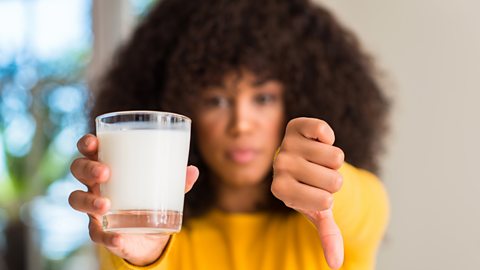 glass of milk with person putting her thumb down to it 