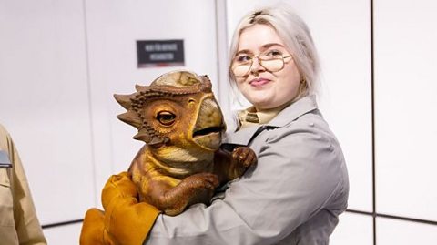 A person holding a baby dinosaur model.