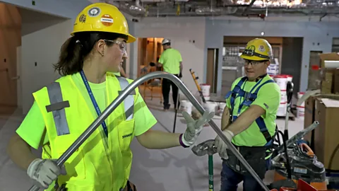 Getty Images Alicia Miksic, an apprentice electrician, bends an electrical pipe with electrician Adam DeFilippo in Boston in 2020 (Credit: Getty Images)