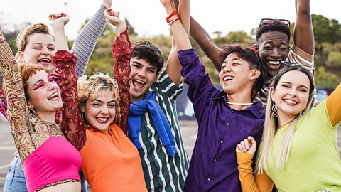 Group of teenagers celebrating the end of term, waving their hands in the air and smiling