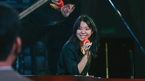 Getty Images Asian woman smiling and singing (Credit: Getty Images)