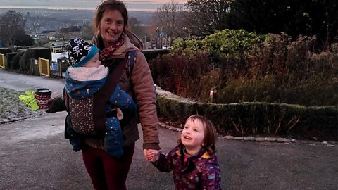 Rebecca with son Finlay in a sling and Ayla in the park.