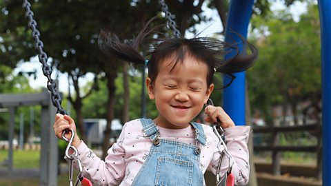 A little girl on the swings.