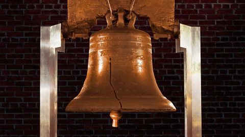 A large bell with a crack half way up the middle.