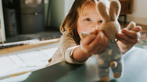 Little girl playing with stuffed toy rabbit