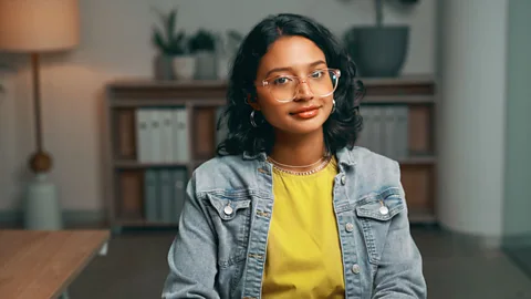 Gen Z female leader in corporate office wearing glasses