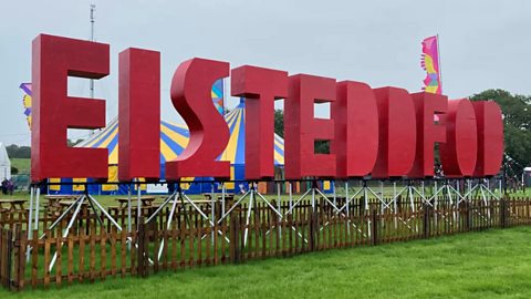 Ffotograff o’r gair ‘Eisteddfod‘ sy’n cael ei arddangos mewn llythrennau mawr coch ar faes yr Eisteddfod bob blwyddyn.