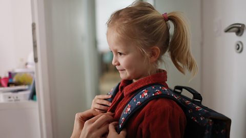 A girl, school bag on her back, ready for starting her first day at primary school