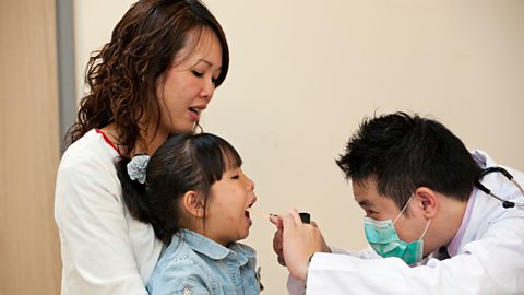 A doctor checks a child's throat