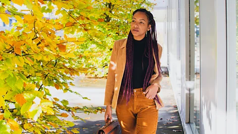 Worker walking among autumn leaves