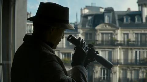 Netflix Fassbender in silhouette with telesope looking out of a window