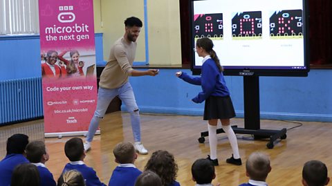 Gyasi Sheppy plays rock, paper, scissors using micro:bits with a primary school pupil.