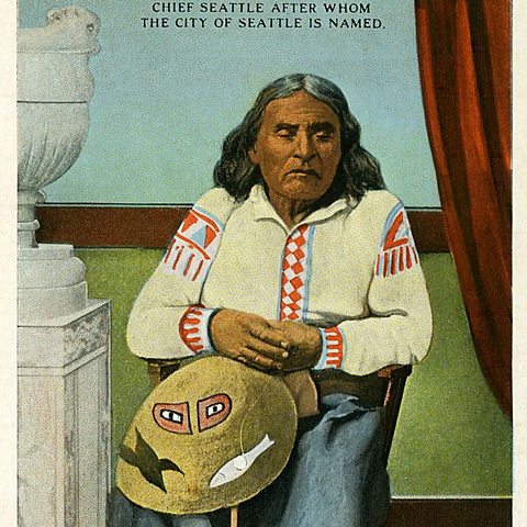 An illustration of Native American Chief Si’ahl, an older man with long grey and black hair, wearing a traditional white shirt with red decorations, sitting on a chair with his eyes closed.