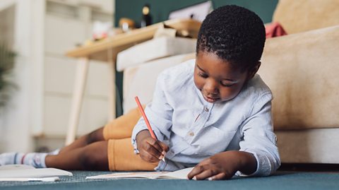 young child draws characters before writing about them in his story