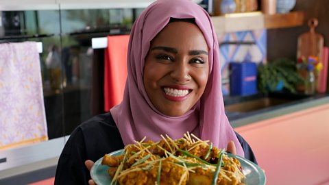 Nadiya Hussain standing with a dish that she has prepared on the new BBC Two series Nadiya's Simple Spices