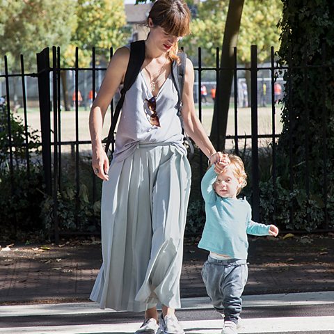 Mother holds childs hand while crossing the road. - stock photo