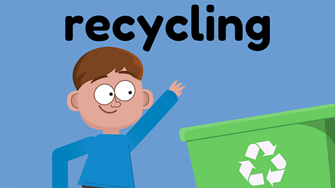 A young boy who has just thrown something into a green recycling bin