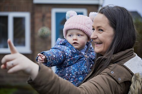 A mother and her child both pointing at something out of frame